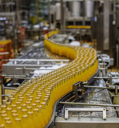 Beverage factory interior. Conveyor flowing with bottles for orange water.