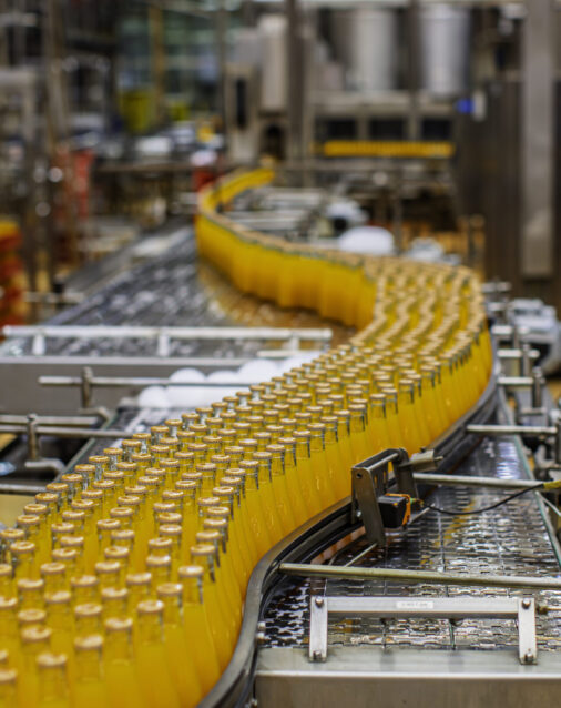 Beverage factory interior. Conveyor flowing with bottles for orange water.