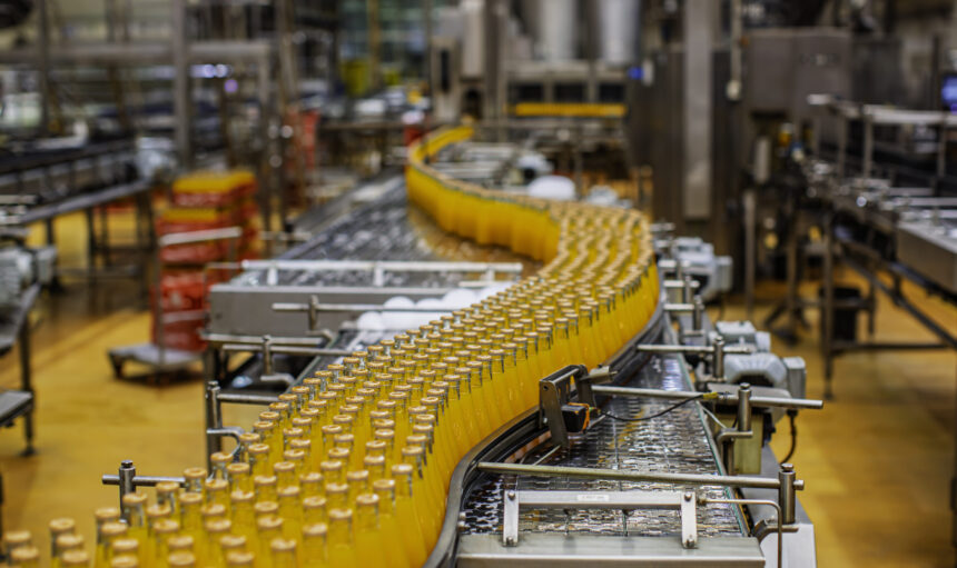 Beverage factory interior. Conveyor flowing with bottles for orange water.