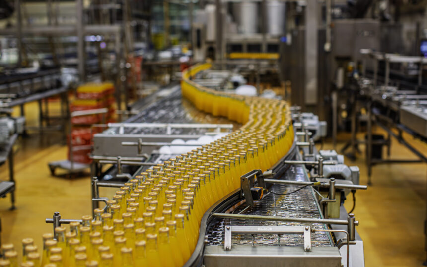 Beverage factory interior. Conveyor flowing with bottles for orange water.