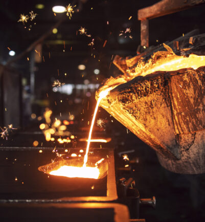 Molten metal casting in foundry. Filling mold with hot liquid iron and producing iron components in steel plant.