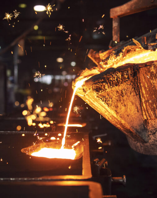 Molten metal casting in foundry. Filling mold with hot liquid iron and producing iron components in steel plant.