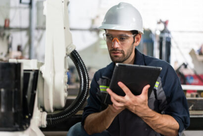 Male automation engineer checking and inspection control a robot arm welding 
machine with tablet in an industrial factory. 
Artificial intelligence concept.