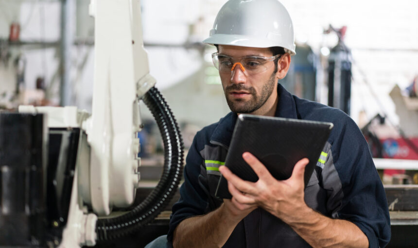 Male automation engineer checking and inspection control a robot arm welding 
machine with tablet in an industrial factory. 
Artificial intelligence concept.