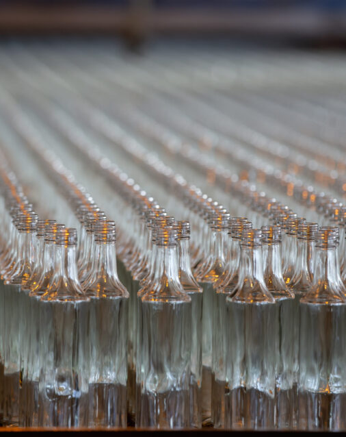 Glassworks. Glass industry. Many glass bottles on a factory conveyor.