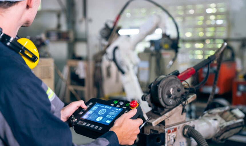 Young factory worker working with adept robotic arm